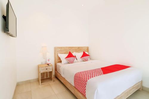 a bedroom with a white bed with red pillows at OYO 2896 Uma Menuh Guest House Near Pantai Keramas in Keramas