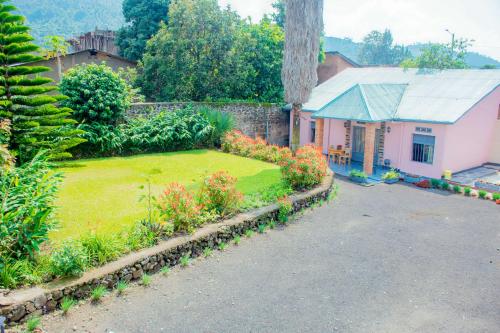 una pequeña casa rosa con un patio con flores en COLIBRI VILLA City Center en Gisenyi