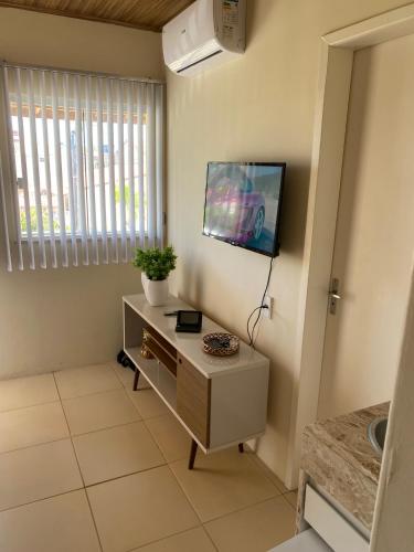 a living room with a tv on a wall at Flat Beira Mar no Condomínio Diver in Vera Cruz de Itaparica
