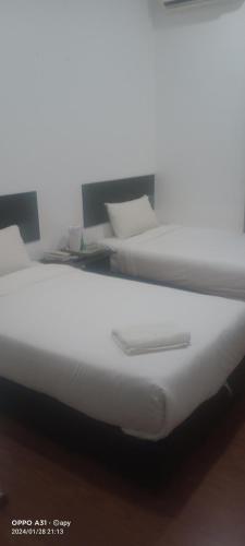 2 weiße Betten nebeneinander in der Unterkunft hotel seri liny in Kuching