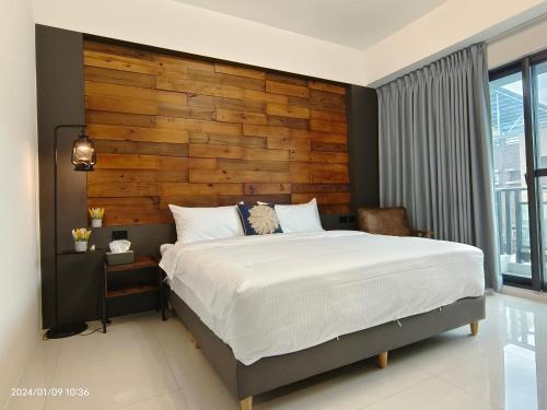 1 dormitorio con 1 cama grande y pared de madera en 墾丁堡雅1號 電梯包棟民宿, en Hengchun