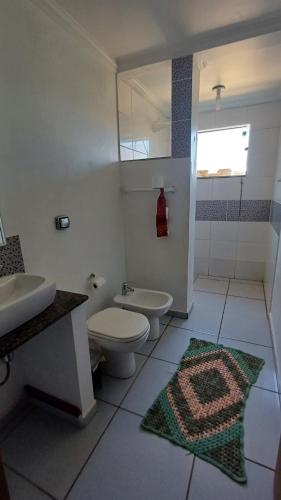 a white bathroom with a toilet and a sink at Casa de Hóspedes Matas do Jacaré de Brotas in Brotas