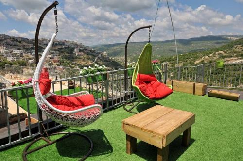 two swing chairs and a table on a balcony at נגיעות בטבע - צימרים כפריים מקסימים כולל ארוחת בוקר ובריכה מחוממת in Bet Dagan