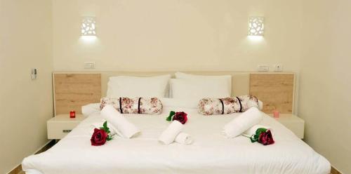 a large white bed with red roses on it at נגיעות בטבע - צימרים כפריים מקסימים כולל ארוחת בוקר ובריכה מחוממת in Bet Dagan