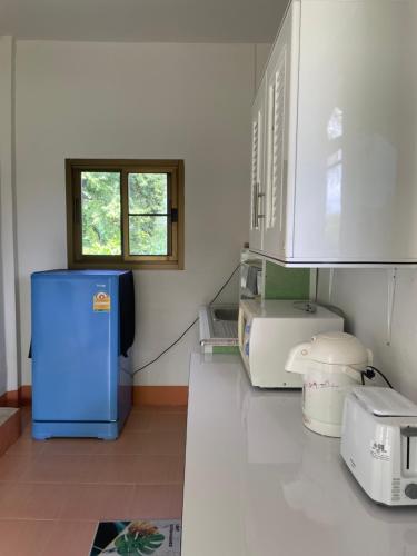 a kitchen with a blue refrigerator and a window at Chalisa Bukit House Lanta in Ban Mo Nae