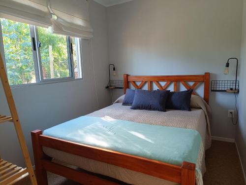 a bedroom with a bed with blue pillows and a window at Frente a la playa en El Pinar in Ciudad de la Costa