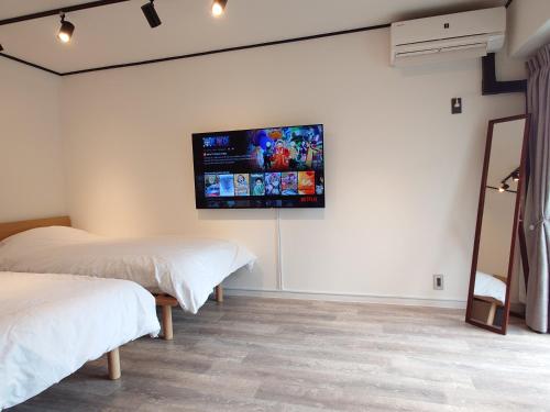 a bedroom with two beds and a flat screen tv on the wall at NIYS apartments 53 type in Tokyo