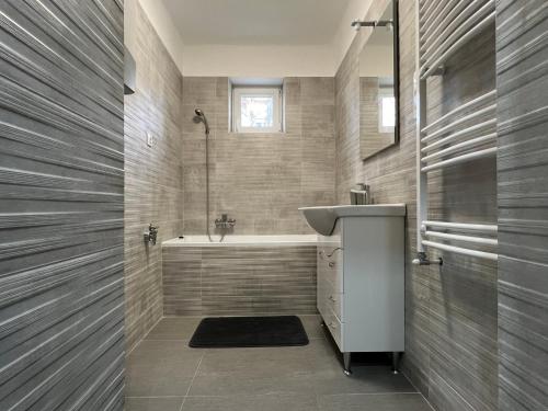 ein Badezimmer mit einem Waschbecken und einer Badewanne in der Unterkunft pecsiapartmanok - K2 Apartman in Pécs