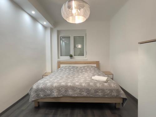 ein weißes Schlafzimmer mit einem Bett und einem Fenster in der Unterkunft pecsiapartmanok - K2 Apartman in Pécs