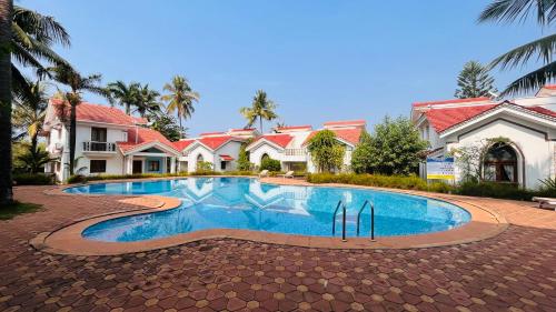 a swimming pool in front of a house at Riveria Foothills & Residency Apartments in Baga