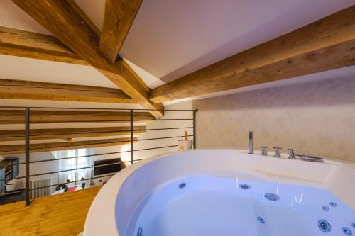 Habitación con bañera blanca grande y techo de madera. en Granduca Mountain Wellness Apartments Campigna, en Campigna