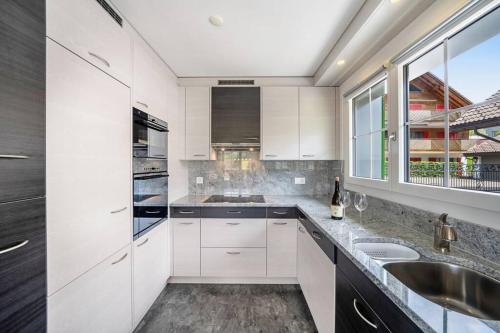 a white kitchen with a sink and a window at helle moderne 3,5-Zimmer-Wohnung 84m2 in Oberiberg