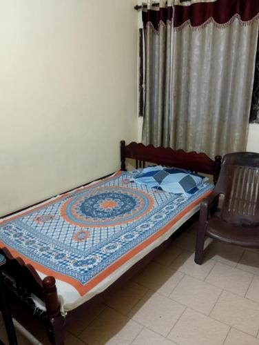 a small bed in a room with a chair at St. Antonys Lodge in Cochin