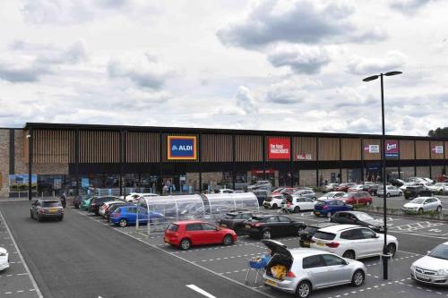 a parking lot with cars parked in front of a building at The Naburn - 3 Bed House with Free Parking & Close to City Centre in Glasgow