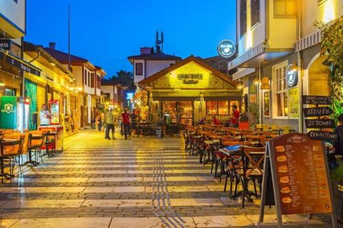 a street with tables and chairs in a town at night at Cozy Midtown Flat in Antalya T2 in Antalya