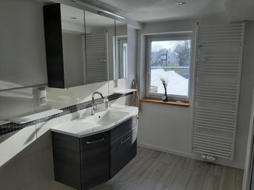 La salle de bains est pourvue d'un lavabo, d'un miroir et d'une fenêtre. dans l'établissement Gemütliche Ferienwohnung der Familie Hüther, à Göttingen