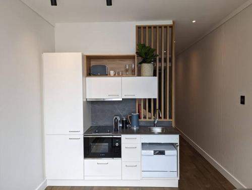 Una cocina con gabinetes blancos y un fregadero. en Trendy studio at the Barracks on Bree, en Ciudad del Cabo
