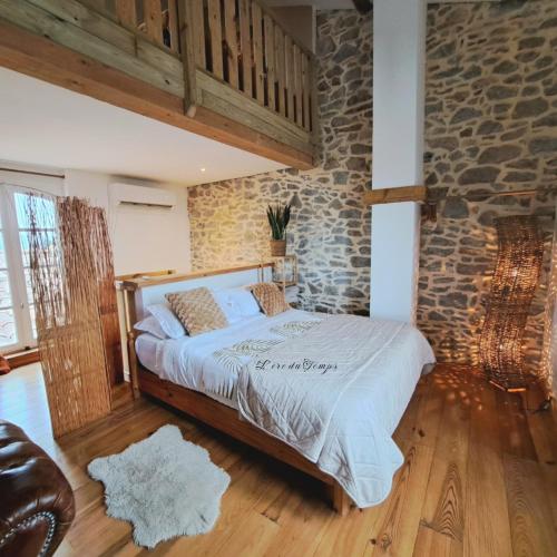 1 dormitorio con cama y pared de piedra en La Maison du Canal - Vue Canal - L'ère du Temps en Homps