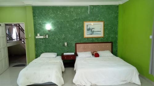 a green room with two beds and a green wall at D' Bunga Hotel Bukit Bunga Bilik Family Deluxe in Batu Karang
