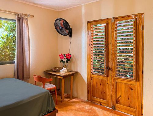 a bedroom with a bed and a table and a window at La Hacienda Hostel in Las Galeras