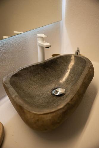 a bathroom with a stone sink with a faucet at Kallichoron Art Boutique Hotel in Astypalaia Town