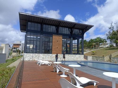 a building with a pool and tables and chairs at CASA NO CONDOMÍNIO CAMINHO DA SERRA in Bananeiras
