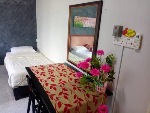 a room with a mirror and a table with flowers on it at D' Bunga Hotel Bukit Bunga Bilik Family Deluxe in Batu Karang