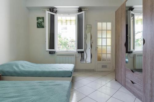 une chambre avec deux lits et deux fenêtres dans l'établissement appartement RDC, à Antibes