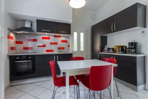 une cuisine avec une table blanche et des chaises rouges dans l'établissement appartement RDC, à Antibes