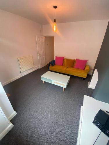 a living room with a yellow couch and pink pillows at SkylinesAirbnb in Stoke on Trent