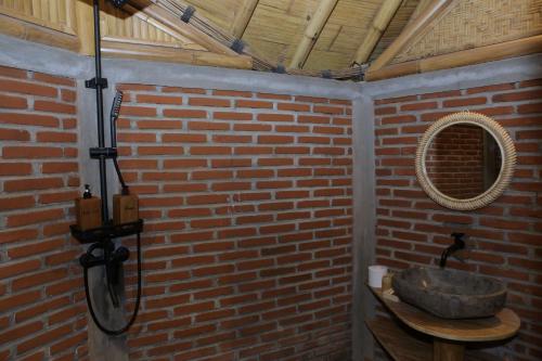 The Osing Bamboo Resort - a LIBERTA Collection في بانيووانجى: حمام مع حوض حجري في جدار من الطوب