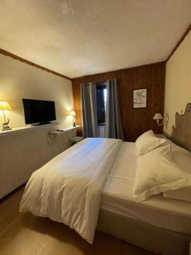 a bedroom with a large white bed and a television at Hotel Ristorante Il Principe in Claviere
