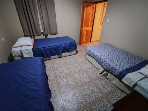 Habitación con 2 camas y pasillo con puerta en Mini departamento en hostal, en San Pedro de Atacama