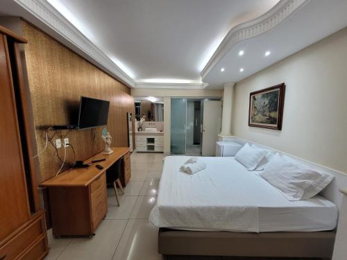 um quarto com uma cama, uma secretária e uma televisão em Apartamento Copacabana Frente Mar no Rio de Janeiro