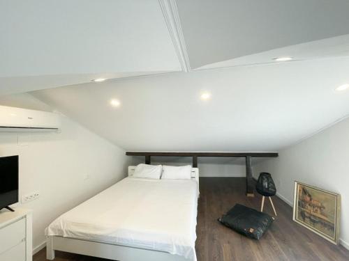 1 dormitorio con 1 cama blanca y TV en Peaceful home in old village en Korčula