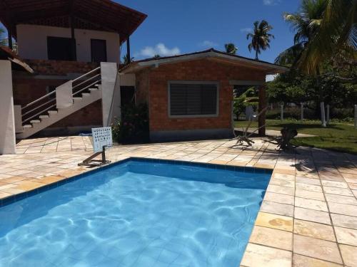 a swimming pool in front of a house at Paraiso Pasargada in Japaratinga