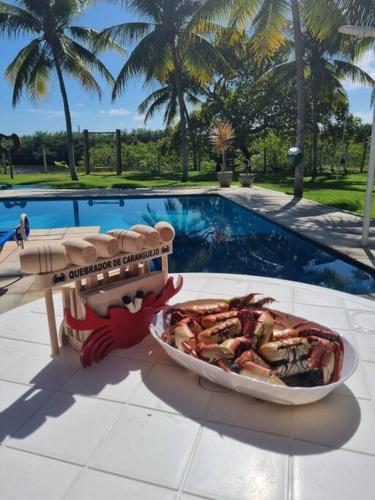 a plate of food on a table next to a pool at Paraiso Pasargada in Japaratinga