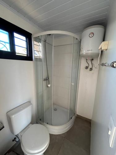 a bathroom with a toilet and a glass shower at Casa Conteiner en campo con playa privada. max 6 personas in Jaureguiberry