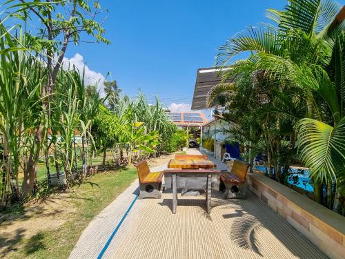 einen Tisch und Stühle auf einem Gehweg mit Bäumen in der Unterkunft Tina's Living Paradise II - Guesthouses with private pool, 5 min to beach in Rayong