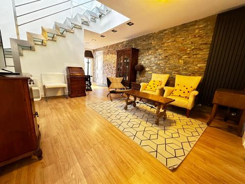 a living room with yellow furniture and a stone wall at Piso centrico en El Espinar in El Espinar
