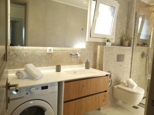a bathroom with a sink and a washing machine at Gialos Holiday House in Agia Pelagia Chlomou