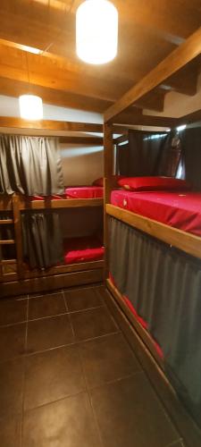 a room with two bunk beds with red sheets at Güemes Hostel Cordoba in Córdoba