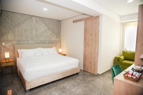 カルタヘナ・デ・インディアスにあるBahía Boutique Houseのベッドルーム(白いベッド1台、緑の椅子付)