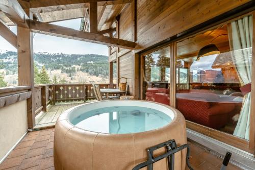 un jacuzzi en el balcón de una cabaña en 70m des pistes de ski, Superbe CHALET avec jacuzzi et 3 stationnements gratuits en Les Gets