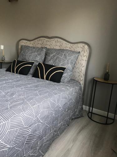 a bed with black and white sheets and pillows at Maison 6 chambres in Beauvais