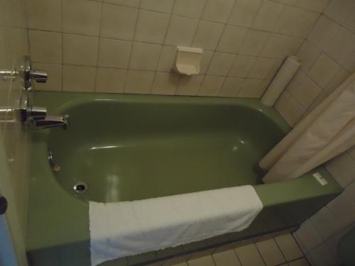 a green bath tub in a bathroom with a towel at Hôtel-Motel Le Pharillon in Cap-des-Rosiers