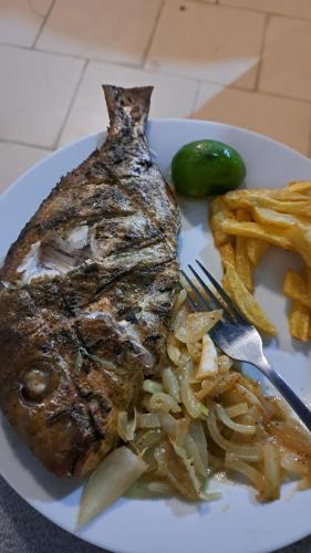 um prato de comida com um pedaço de peixe e batatas fritas em La Fandenoise em Thiès