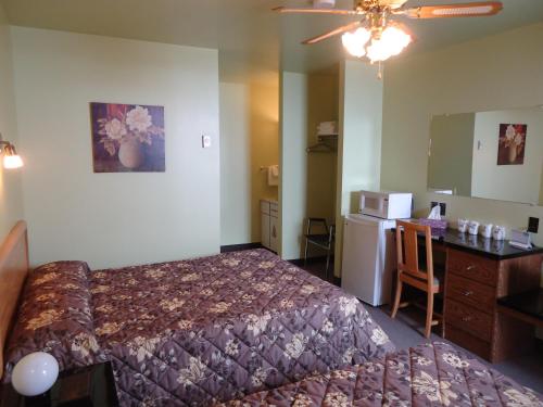 a hotel room with a bed and a desk and a kitchen at Hôtel-Motel Le Pharillon in Cap-des-Rosiers