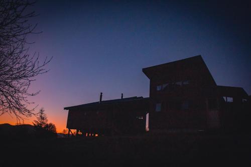 a silhouette of a building with the sunset in the background at Espíritus del Cañi. Tiny home y destilería in Pucón
