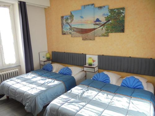 a bedroom with two beds and a painting on the wall at Hotel De La Gare in Montluçon